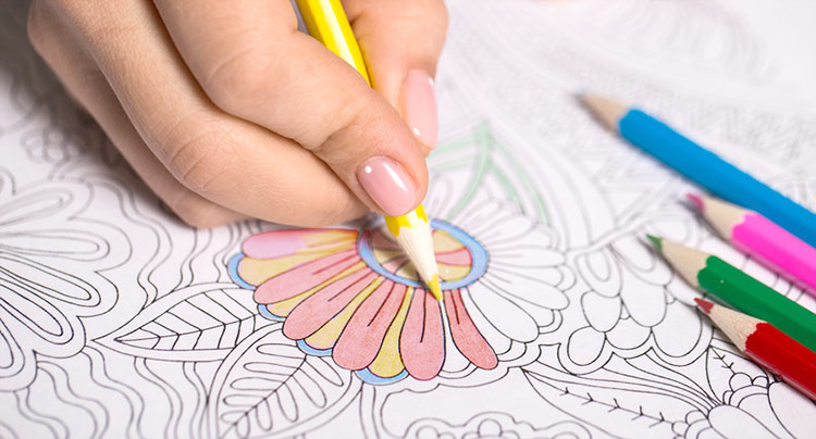 young woman fills in a coloring picture with colored pencils