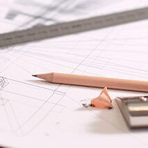 Bleistift mit Spitzer und Lineal, Bauplan im Hintergrund